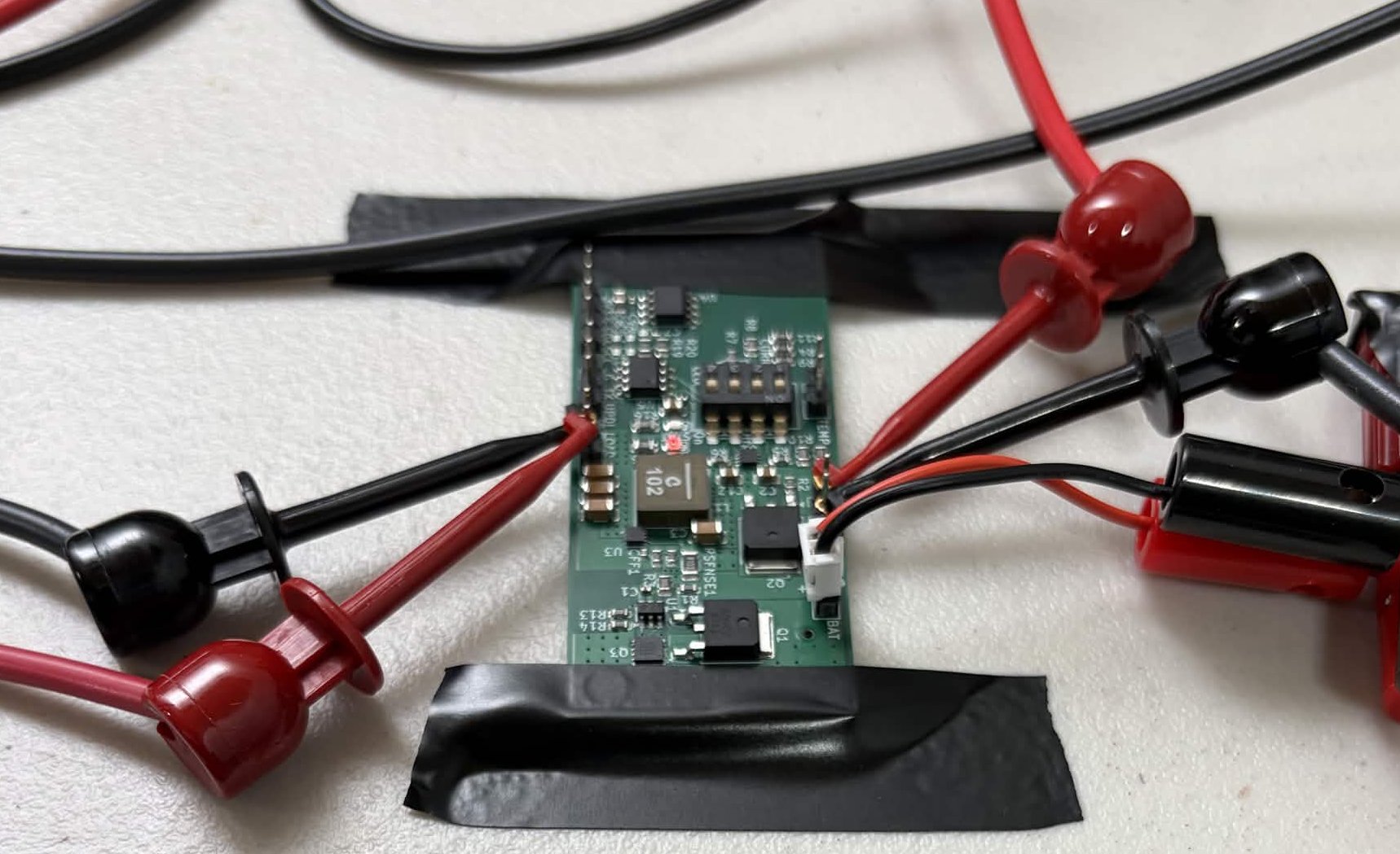 A LiFePV Power Module prototype on a workbench, connected to multimeter probes for testing.
